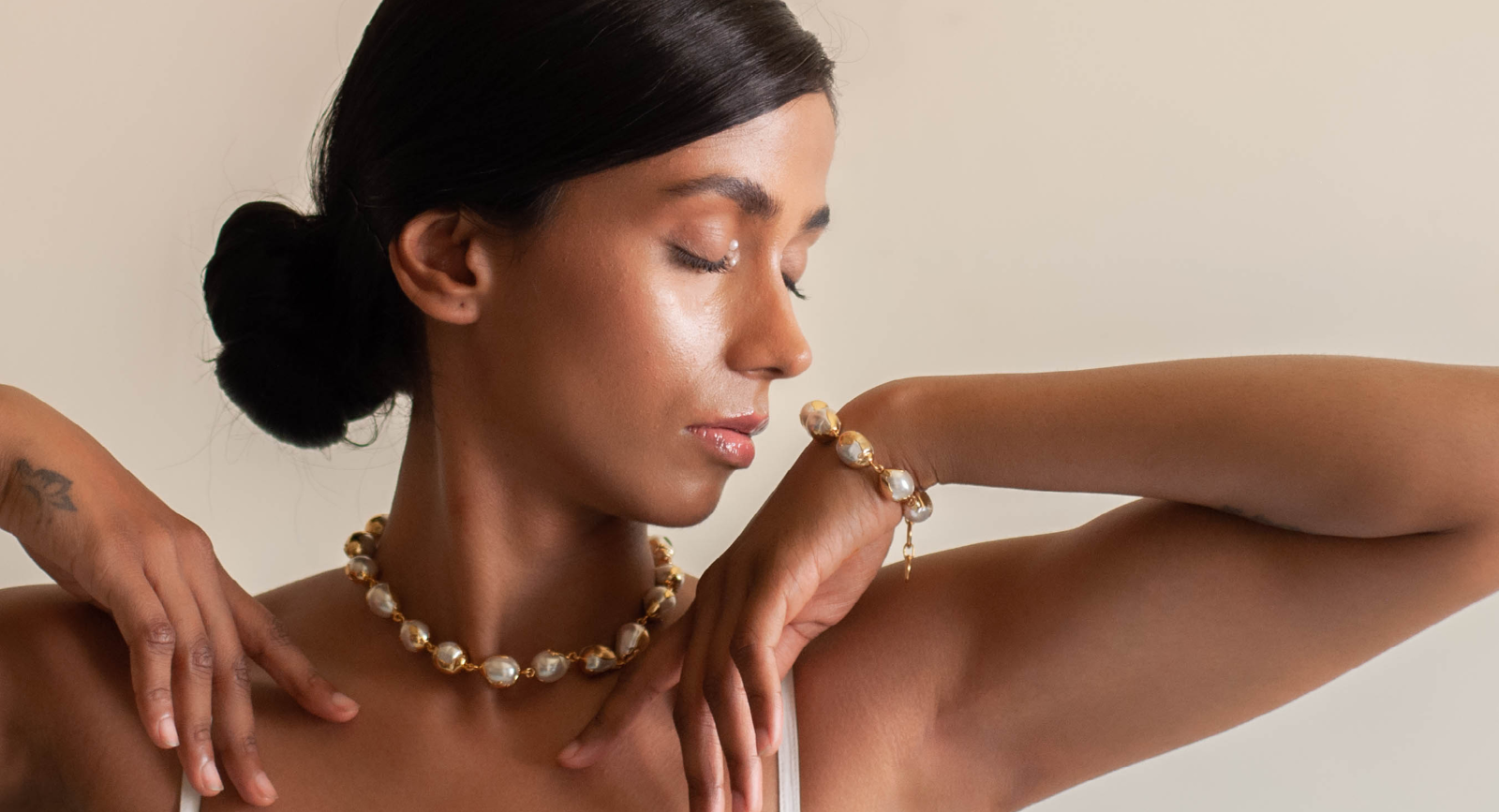 Woman wearing pearl jewelry against a neutral background