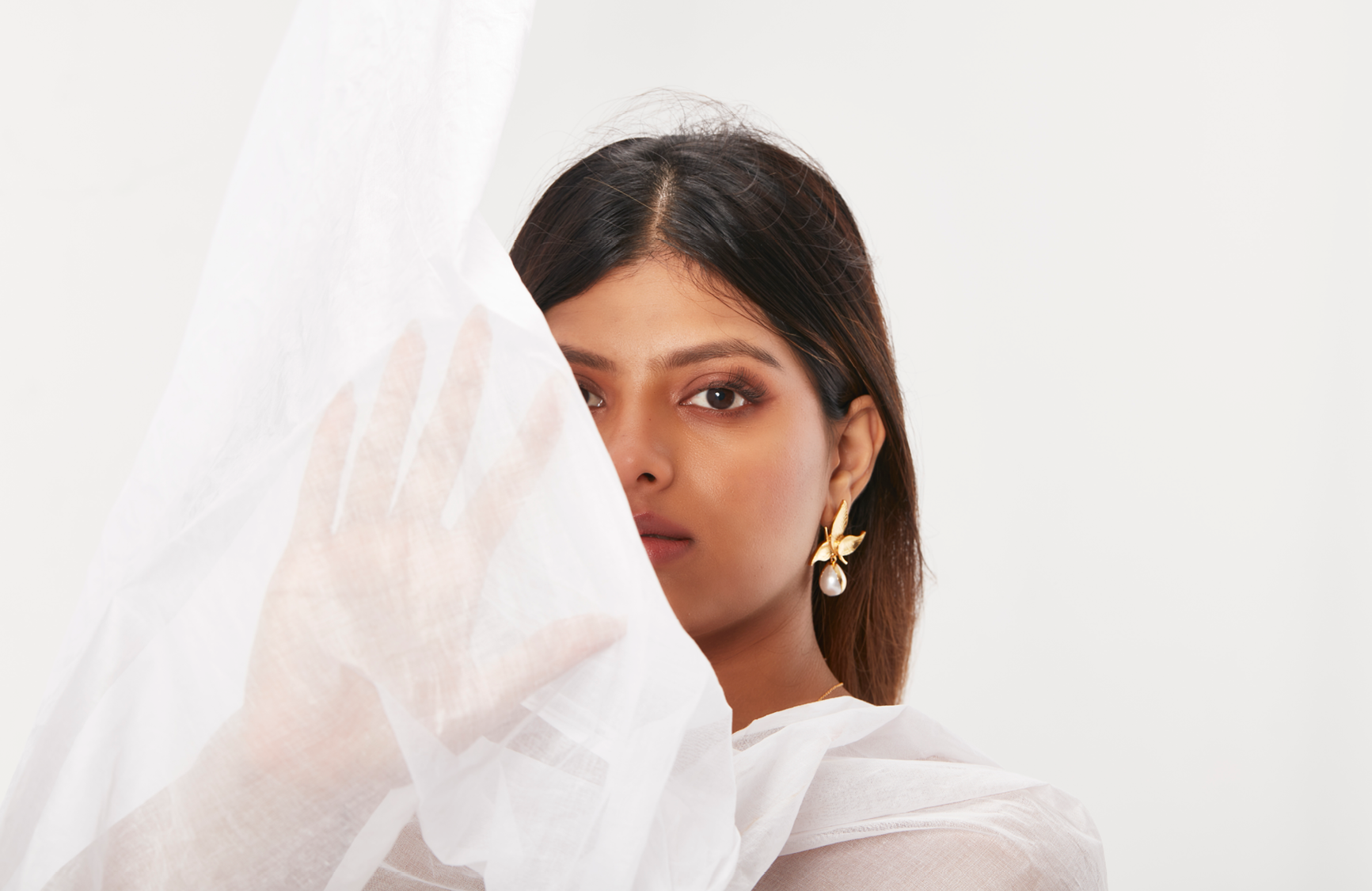 Woman wearing a white saree with a plain background
